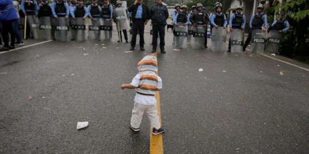 道路を封鎖する警官たちと、移民の子ども