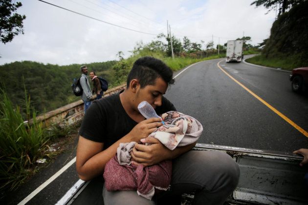 移動中のトラックの荷台で、赤ん坊にミルクを与える男性