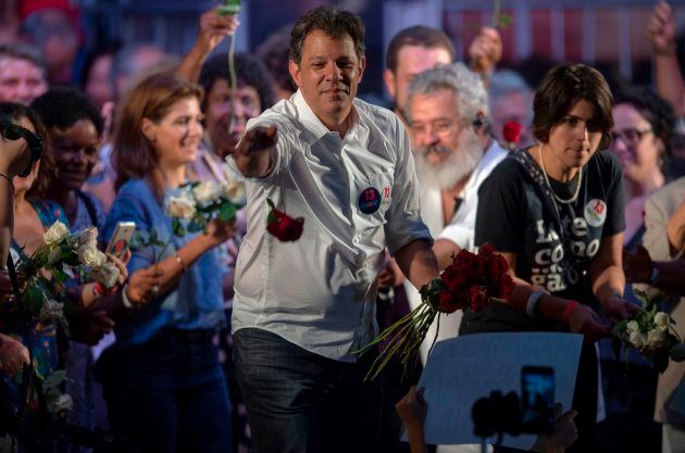 集会で支持者に花を配るフェルナンド・アダジ氏＝10月23日、リオデジャネイロ