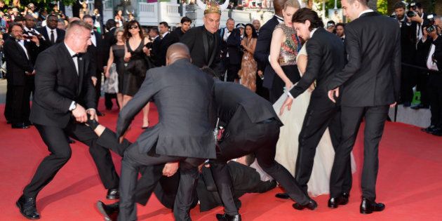 CANNES, FRANCE - MAY 16: A man invades the Red Carpet and is held by security at the 'How To Train Your Dragon 2' premiere during the 67th Annual Cannes Film Festival on May 16, 2014 in Cannes, France. (Photo by Pascal Le Segretain/WireImage)