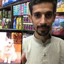 愛猫を自慢するウマルさん。ウマルサンの携帯電話には飼い猫の画像が写っている。（2018年10月）