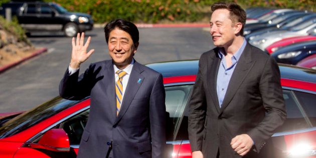 Japanese Prime Minister Shinzo Abe stands with Tesla CEO Elon Musk after returning from a brief test ride at Tesla's headquarters in Palo Alto, Calif., Thursday, April 30, 2015. (AP Photo/Noah Berger)