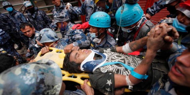 Pemba Tamang is carried on a stretcher after being rescued by Nepalese policemen and U.S. rescue workers from a building that collapsed five days ago in Kathmandu, Nepal, Thursday, April 30, 2015. Crowds cheered Thursday as a Tamang was pulled, dazed and dusty, from the wreckage of a seven-story Kathmandu building that collapsed around him five days ago when an enormous earthquake shook Nepal. (AP Photo/Niranjan Shresta)