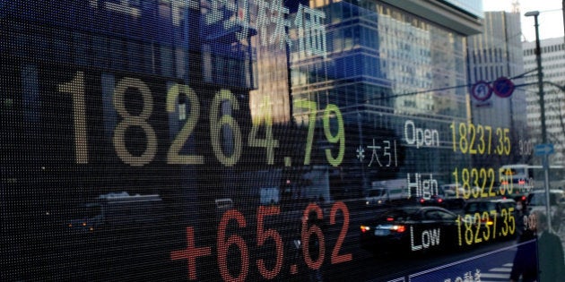 A pedestrian is reflected in an electronic stock board displaying the closing figure of the Nikkei 225 Stock Average outside a securities firm in Tokyo, Japan, on Thursday, Feb.19, 2015. Japan stocks rose, pushing the Nikkei 225 Stock Average to the highest close in 15 years, as the biggest banks jumped and Trend Micro Inc. and Sony Corp. gained. Photographer: Yuriko Nakao/Bloomberg via Getty Images