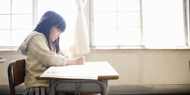 Girl (8-9) writing in school classroom