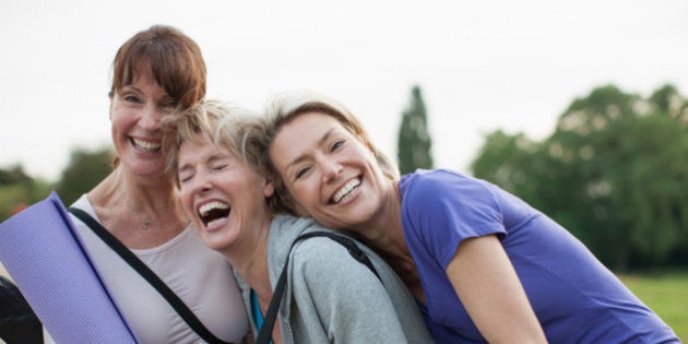 Smiling women holding yoga mats