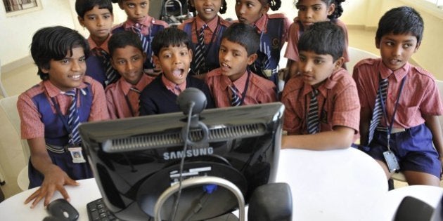 HYDERABAD, INDIA - DECEMBER 17: Students of the New Little Scholars School interact during an online session with Mrs Helen Schofield from Islington, London in the outskirts of Hyderabad on December 17, 2009. Skype grannies in Britain are spending their free time reading stories and singing nursery rhymes to children living in Indian slums. The pensioners log on to the internet from their cozy living rooms to educate poverty-stricken youngsters sitting round a computer screen in their classroom. Skype Grannies is a groundbreaking concept from Newcastle University Professor Sugata Mitra, the man better known as the Slumdog Professor after he was revealed as the inspiration behind Oscar winning film Slumdog Millionaire. Prof Mitra asked slum children who they would most like to speak to over the internet and they asked for British grandmothers to read them stories. He set out recruiting a team of British women to spend a few hours week as volunteer teachers. Helen Schofield, 64, from Islington, north London, is one of the team who reads every week to children at the New Little Scholars School in Hyderabad. (Photo by Niklas Halle'n/Barcroft India / Getty Images)