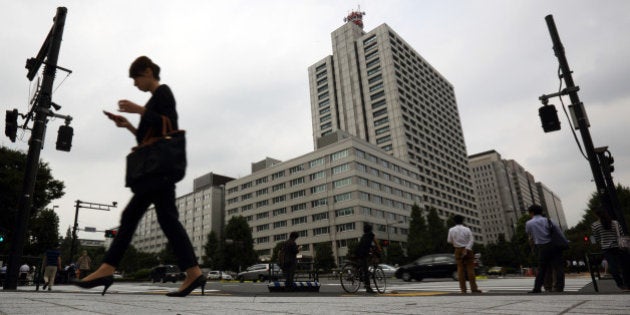 A woman using a mobile phone walks through the Kasumigaseki area of Tokyo, Japan, on Thursday, Sept. 11, 2014. Losing women from the workforce in their 20s and 30s to look after children is no longer an option for Japan as its aging workforce means there will be fewer and fewer men to fill the positions. Photographer: Tomohiro Ohsumi/Bloomberg via Getty Images