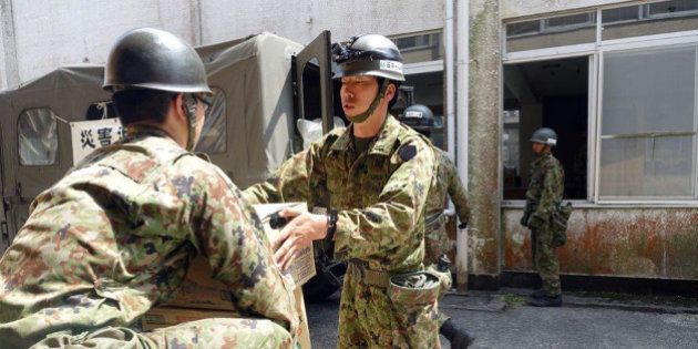 Troops bring in supplies to set up a new shelter in Minamiaso, Kumamoto prefecture, Japan Tuesday, April 19, 2016. Evacuees at a gymnasium were moving to another shelter Tuesday, a nearby former elementary school, because some expressed fears after the strong aftershock, because the gym stands on the hill. (AP Photo/Mari Yamaguchi)