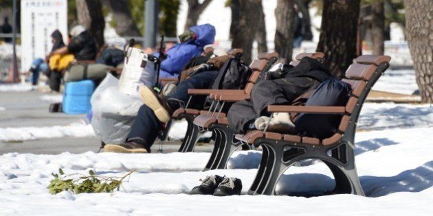 Homeless men take naps on benches at a park in Tokyo on February 16, 2014 after a snow storm hit Japan. Two people were killed when a fresh snow storm hit Japan, disrupting rail and road travel, grounding more than 100 flights and adding to the piles left behind by an earlier blanketing. AFP PHOTO/Toru YAMANAKA (Photo credit should read TORU YAMANAKA/AFP/Getty Images)