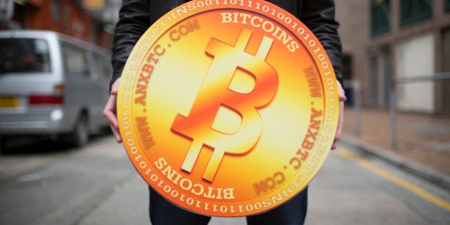 A man poses for a photograph with a mock Bitcoin outside the ANXBTC store, operated by the ANX Bitcoin exchange, in Hong Kong, China, on Friday, Feb. 28, 2014. ANX, a Hong Kong-based platform for trading virtual currencies, opened the first retail store in the city that allows individuals to buy and sell Bitcoins in Hong Kong dollars. Photographer: Brent Lewin/Bloomberg via Getty Images