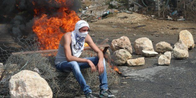 A Palestinian student from Palestine Polytechnic University sits during a protest against Israel near the Jewish settlement of Beit Hagai, at the southern entrance to the occupied West Bank city of Hebron, on October 18,2015. Israel on Sunday rejected a proposal to send international observers to a flashpoint holy site in a bid to calm more than two weeks of unrest after five more stabbing incidents defied a security crackdown. AFP PHOTO/HAZEM BADER (Photo credit should read HAZEM BADER/AFP/Getty Images)