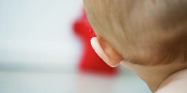 Baby with head turned toward toy, rear cropped view, close-up