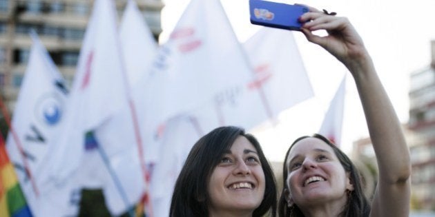 A couple takes a selfie during the celebration of the approval of the first law that would allow same-sex couples to enter into civil unions in Santiago on January 28, 2015. Congress on Wednesday approved -by a 78-9 vote margin- the country's first law authorizing civil unions of gay and lesbian couples. The law, which has been in the works for four years, gives legal recognition to unmarried couples and ensures their rights to receive pensions, enroll in health plans and inherit property from one another. AFP PHOTO/VLADIMIR RODAS (Photo credit should read VLADIMIR RODAS/AFP/Getty Images)