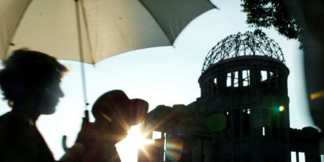 Japanese women walk past the gutted A-bomb dome in Peace Memorial Park in Hiroshima, Japan August 6, 2003. REUTERS/Toshiyuki Aizawa/File Photo