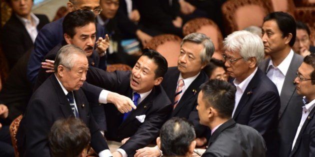 Opposition lawmakers surround chairman Yoshitada Konoike (L) as lawmaker Masahisa Sato (2nd L) gestures during the Upper House's ad hoc committee meeting on the controversial security bills, at the National Diet in Tokyo on September 17, 2015. Japan's ruling and opposition parties remained deadlocked in parliament early on September 17 over proposed security bills as thousands took to the streets in protests against legislation that could see troops fight overseas for the first time in 70 years. AFP PHOTO / Yoshikazu TSUNO (Photo credit should read YOSHIKAZU TSUNO/AFP/Getty Images)