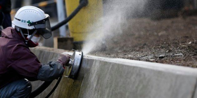 A worker uses a high pressure water washing machine during a radioactive decontamination at a private residence in Tomioka town, Fukushima prefecture, near Tokyo Electric Power Co's (TEPCO) tsunami-crippled Fukushima Daiichi nuclear power plant February 24, 2015. Many residents of Okuma, a village near the stricken Fukushima Daiichi plant, are angry about government plans to dump some 30 million tons of radioactive debris raked up after the March 2011 nuclear disaster in a sprawling waste complex on their doorstep. Few believe Tokyo's assurances that the site will be cleaned up and shut down after 30 years. In the four years since the disaster, Japan has allocated over $15 billion to lower radiation levels around the plant. Every day, teams of workers blast roads with water, scrub down houses, cut branches and scrape contaminated soil off farmland. That radiated trash now sits in plastic sacks across the region, piling up in abandoned rice paddies, parking lots and even residents' backyards. REUTERS/Toru Hanai (JAPAN - Tags: DISASTER ENERGY ENVIRONMENT)PICTURE 15 OF 27 FOR WIDER IMAGE STORY 'RADIOACTIVE FUKUSHIMA - FOUR YEARS ON'SEARCH 'OKUMA TORU' FOR ALL IMAGES