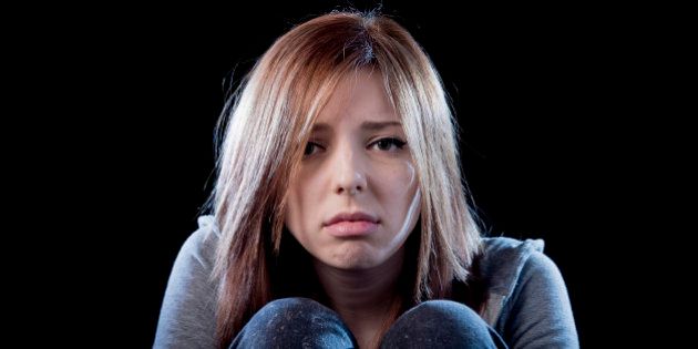 young beautiful teenager girl with red hair feeling lonely and scared looking sad and desperate suffering depression as victim of cyber bullying or social abuse violence and rejection