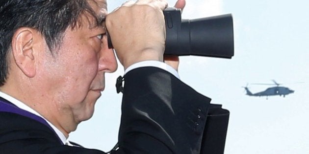 Japanese Prime Minister Shinzo Abe looks at Japanese Maritime Self-Defense Force naval ships through binoculars during a fleet review off Sagami Bay, Kanagawa prefecture, on October 18, 2015. Thirty-six MSDF vessels and navy ships from Australia, India, France, South Korea and the United States participated in the fleet review. AFP PHOTO / JIJI PRESS JAPAN OUT (Photo credit should read JIJI PRESS/AFP/Getty Images)