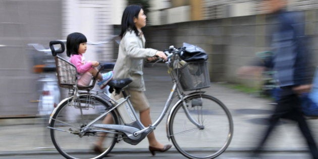 JAPAN-EDUCATION-SOCIETY-CHILDREN, FEATURE, BY MIWA SUZUKI A mother pushes her bicycle carrying her daughter she picked up from a nursery school in Tokyo on March 19, 2010. Parents known as 'monsters' for their aberrant demands have been pushing nursery and school workers over the edge, so much so that some teachers killed themselves, in a nation with one of the world's lowest birthrates. AFP PHOTO / Yoshikazu TSUNO (Photo credit should read YOSHIKAZU TSUNO/AFP/Getty Images)