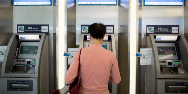 A woman uses an automated teller machine (ATM) inside a Standard Chartered Plc bank branch in Hong Kong, China, on Wednesday, March 21, 2014. Standard Chartered Plc, which makes three-quarters of its earnings in Asia, cut bonuses and indicated that capital levels can weather writedowns after the banks first annual profit drop in a decade. Photographer: Brent Lewin/Bloomberg via Getty Images