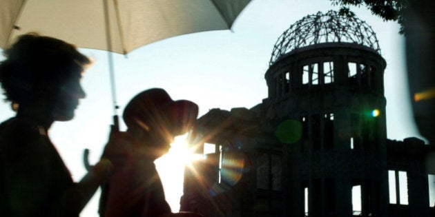 Japanese women walk past the gutted A-bomb dome in Peace Memorial Park in Hiroshima, Japan August 6, 2003. REUTERS/Toshiyuki Aizawa/File Photo