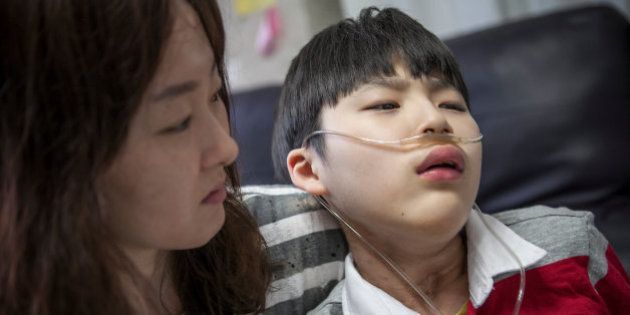 YONGIN, SOUTH KOREA - MAY 06: Kwon Mi-ae, mother of Lim Seong-joon, 13, who is suffering from chronic lung disease, comforts him after he was feeling a light nausea while at their home on May 6, 2016 in Yongin, South Korea. His mother bought a humidifier sterilizer called 'Oxy Humidifier on Duty' back in 2003, and used the product with a humidifier for more than a year, subsequently damaging the lungs of Seong-joon. Seong-joon has gone through operations and now is living off of an oxygen tank 24 hours a day. His mother, Kwon Mi-ae, said that she thought of killing herself many times, but decided to live for him. Beginning in 2001, Reckitt Benckiser Korea (known as Oxy prior to 2014) used Polyhexamethylene guanidine (PHMG) in a humidifier sterilizer product called Oxy Ssak Ssak; the ingredient was dropped in 2011 when the Korea Centers for Disease Control and Prevention (KCDC) published a report showing a link between the compound and lung damage and deaths. Several companies in South Korea made humidifier sterliizers with poisonous ingredients between 2001 and 2011. According to a BBC report in May 2016, about 500 people, many of them women and children, are reported to have died or been injured after inhaling these ingredients. One of the victims's fathers is visiting U.K. right now, and a few other victims's families are planning to visit the U.K. at the end of May. The U.K.-based firm Reckitt Benckiser has admitted and apologized for selling a humidifier disinfectant that killed more than 100 people in South Korea on May 2, 2016. (Photo by Jean Chung/Getty Images)