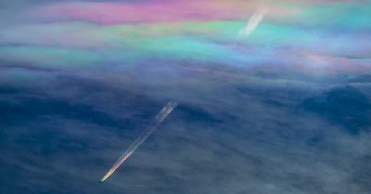 虹色の飛行機雲が、虹色の「彩雲」をくぐり抜ける（画像
