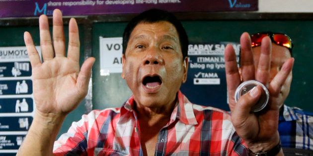 Front-running presidential candidate Mayor Rodrigo Duterte gestures at photographers to move back prior to voting in a polling precinct at Daniel R. Aguinaldo National High School at Matina district, his hometown in Davao city in southern Philippines Monday, May 9, 2016. Duterte was the last to vote among five presidential hopefuls. (AP Photo/Bullit Marquez)