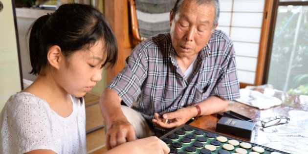 Granddaughter and grandfather playing Othello / Reversi, in cozy Japanese house.