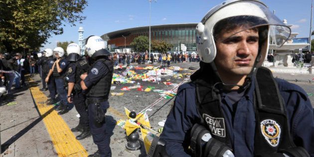 Turkish police officers secure the area at the site of an explosion, where the bodies of victims were covered with flags and banners, in Ankara, Turkey, Saturday, Oct. 10, 2015. The two bomb explosions targeting a peace rally in the capital Ankara has killed dozens of people and injured scores of others. The explosions occurred minutes apart near Ankara's main train station as people were gathering for the rally, organized by the country's public sector workers' trade union and other civic society groups. The rally aimed to call for an end to the renewed violence between Kurdish rebels and Turkish security forces. (AP Photo/Burhan Ozbilici)