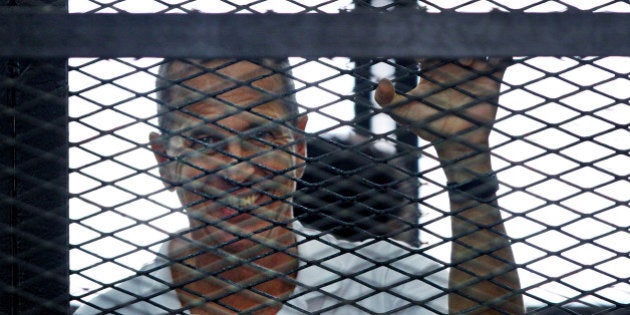 Al-Jazeera journalist Peter Greste looks out from the defendant's cage during the sentencing hearing for journalists working for Al-Jazeera in a courtroom in Cairo, Egypt, Monday, June 23, 2014. An Egyptian court on Monday convicted three journalists from Al-Jazeera English and sentenced them to seven years in prison each on terrorism-related charges, bringing widespread criticism that the verdict was a blow to freedom of expression. The three, Australian Peter Greste, Canadian-Egyptian Mohamed Fahmy and Egyptian Baher Mohammed, have been detained since December charged with supporting the Muslim Brotherhood, which has been declared a terrorist organization, and of fabricating footage to undermine Egypt's national security and make it appear the country was facing civil war. (AP Photo/Ahmed Abd El Latif, El Shorouk Newspaper) EGYPT OUT