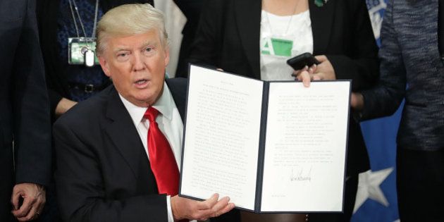 U.S. President Donald Trump, center, holds up a signed executive order at the Department of Homeland Security (DHS) in Washington, D.C. U.S., on Wednesday, Jan. 25, 2017. Trump acted on two of the most fundamental -- and controversial -- elements of his presidential campaign, building a wall on the border with Mexico and greatly tightening restrictions on who can enter the U.S. Photographer: Chip Somodevilla/Pool via Bloomberg
