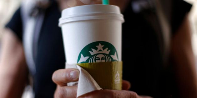 In this May 31, 2014 photo, a woman holds a coffee drink outside a Starbucks in downtown Chicago. Starbucks is raising prices on some of its drinks by 5 cents to 20 cents starting next week, and customers can also soon expect to pay $1 more for the packaged coffee it sells in supermarkets. Prices for medium and large brewed coffees, which are known as Grande and Venti, respectively, will go up between 10 cents and 15 cents in most U.S. markets, the company said. (AP Photo/Gene J. Puskar)