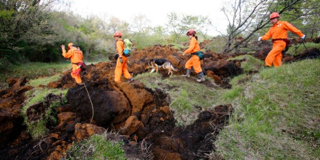Rescuers and a search dog check the damage around a landslide area caused by earthquakes in Minamiaso, Kumamoto prefecture, Japan, Sunday, April 17, 2016. Two nights of increasingly terrifying earthquakes flattened houses and triggered major landslides in southern Japan. (AP Photo/Shizuo Kambayashi)