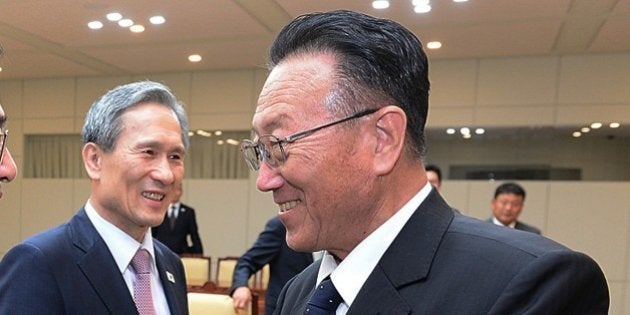 In this photo provided by the South Korean Unification Ministry, South Korean Unification Minister Hong Yong-pyo, left, shakes hands with Kim Yang Gon, right, a senior North Korean official responsible for South Korean affairs, as South Korean presidential security adviser Kim Kwan-jin looks on after their meeting at the border village of Panmunjom in Paju, South Korea, Tuesday, Aug. 25, 2015. South Korea has agreed to halt propaganda broadcasts at noon Tuesday after North Korea expressed regret over a recent land mine blast that maimed two South Korean troops, both Koreas announced after three days of intense talks aimed at defusing soaring tension between the rivals.(The South Korean Unification Ministry via AP)