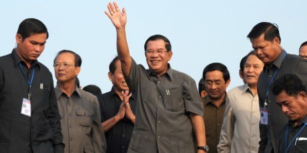 Cambodian Prime Minister Hun Sen (C) greets people during a ceremony for casting concrete to connect Neak Loeung bridge in Kandal province on January 14, 2014. Cambodian strongman Hun Sen marked three decades as premier on January 14, hailing his role in rebuilding the war-torn nation, as rights groups lambasted him for using 'violence, repression and corruption' to cling onto power. AFP PHOTO / TANG CHHIN SOTHY (Photo credit should read TANG CHHIN SOTHY/AFP/Getty Images)