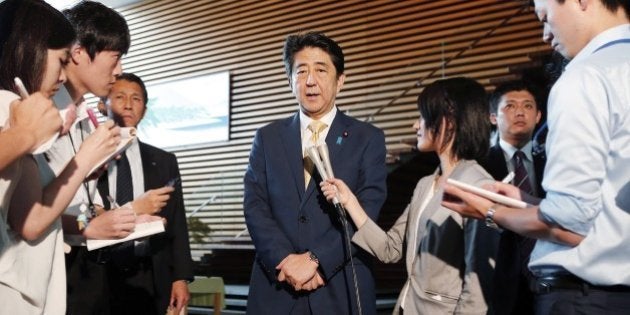 Japan's Prime Minister Shinzo Abe (C) is surrounded by reporters as he speaks at his official residence in Tokyo on July 16, 2015 after passing controversial security bills at the country's parliament. Controversial security bills that opponents say will undermine 70 years of pacifism and could see Japanese troops fighting abroad for the first time since World War II, passed through the powerful lower house of parliament. JAPAN OUT AFP PHOTO / JIJI PRESS (Photo credit should read JIJI PRESS/AFP/Getty Images)