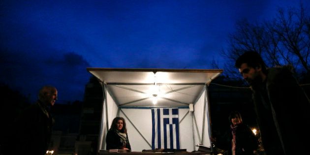 A Greek flag is seen inside a kiosk of the New Democracy party, as people walk by in Athens on Tuesday, Jan. 20, 2015. Weekend opinion polls showed conservative Prime Minister Antonis Samaras' New Democracy party trailing the anti-bailout Syriza party in voter support and that a coalition government is likely to emerge from Sunday's vote. (AP Photo/Petros Giannakouris)
