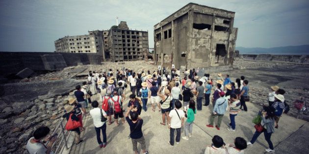 In this June 29, 2015 photo, tourists visit a part of Hashima Island, commonly known as Gunkanjima, which means âBattleship Island,â off Nagasaki, Nagasaki Prefecture, southern Japan. The island is one of 23 old industrial facilities seeking UNESCO's recognition as world heritage âSites of Japanâs Meiji Industrial Revolutionâ meant to illustrate Japan's rapid transformation from a feudal farming society into an industrial power at the end of the 19th century. UNESCOâs World Heritage Committee is expected to approve the proposal during a meeting being held in Bonn, Germany, through July 9. (AP Photo/Eugene Hoshiko)