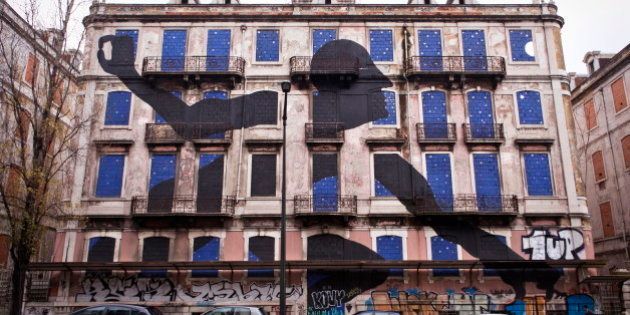 A giant man is sticking out his head and arms of the windows of an old abandoned building. The art piece is made by street artist Sam3 who is one out of 16 artists who took part in the Crono Project in Lisbon. Portugal 2013. (Photo by: PYMCA/UIG via Getty Images)