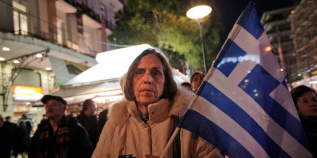 A supporter of Greece's conservative New Democracy party, holding the national flag, waits to greet the party's leader and Prime Minister Antonis Samaras, during a visit in Athens, Tuesday, Jan. 20, 2015. Samaras' party has failed so far to overcome a gap in opinion polls with the anti-bailout Syriza party ahead of the Jan. 25 general election. Weekend opinion polls showed New Democracy party trailing the anti-bailout Syriza party in voter support and that a coalition government is likely to emerge from Sunday's vote. (AP Photo/Lefteris Pitarakis)