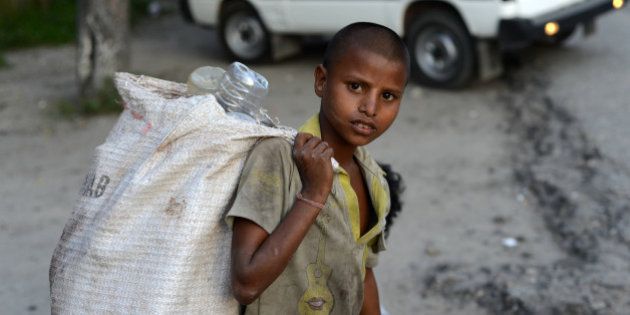 A young Indian ragpicker looka on as he collects used mineral water bottles in Siliguri on June 12, 2013, on World Day Against Child Labour. The International Labour Organization (ILO) launched the first World Day Against Child Labour in 2002 as a way to highlight the plight of children engaged in work that deprives them of adequate education, health, leisure and basic freedoms, violating their rights. AFP PHOTO/Diptendu DUTTA (Photo credit should read DIPTENDU DUTTA/AFP/Getty Images)
