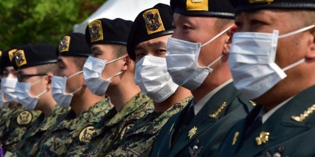 South Korean soldiers wear facemasks during a ceremony marking the 60th anniversary of Korean Memorial Day at the National Cemetery in Seoul on June 6, 2015. South Korea reported on June 5, a fourth death from Middle East Respiratory Syndrome (MERS), as an infected doctor fuelled fears of a fresh surge in cases and prompted Seoul's mayor to declare 'war' on the virus. AFP PHOTO / JUNG YEON-JE (Photo credit should read JUNG YEON-JE/AFP/Getty Images)