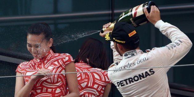 Mercedes AMG Petronas F1 Team's British driver Lewis Hamilton (L) spays attendants on the podium with champagne after his victory in the Formula One Chinese Grand Prix in Shanghai on April 12, 2015. AFP PHOTO / Greg BAKER (Photo credit should read GREG BAKER/AFP/Getty Images)