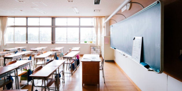 A view of a Japanese school classroom, traditional wooden desks and chairs, and blackboard. Interior shot, nobody, horizontal composition.