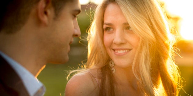 A pretty young girl stares at the eyes of a smart young man stands close to her.