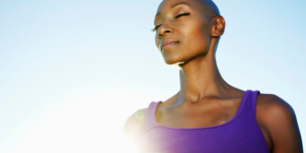 African American woman smiling in sunburst under blue sky