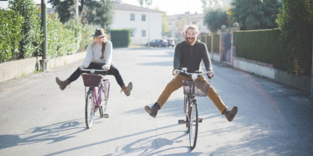 Young couple cycling with legs out