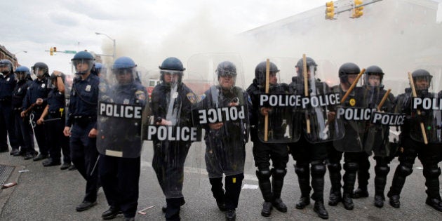 Police advance toward protestors as a store burns, Monday, April 27, 2015, during unrest following the funeral of Freddie Gray in Baltimore. Gray died from spinal injuries about a week after he was arrested and transported in a Baltimore Police Department van. (AP Photo/Patrick Semansky)